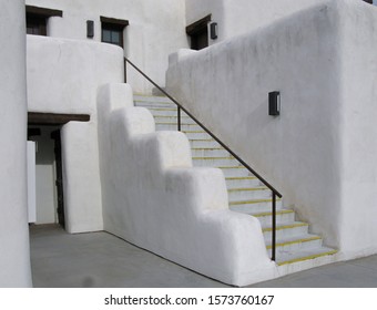 An Adobe Building With Stairs, Doors, And Windows