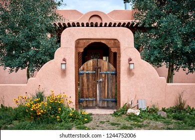 An Adobe Building With A Wooden Gate And Wall