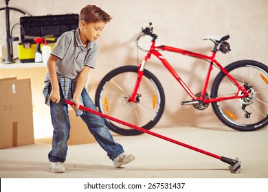 Adolescent Boy With Mop Cleaning Floor In Garage