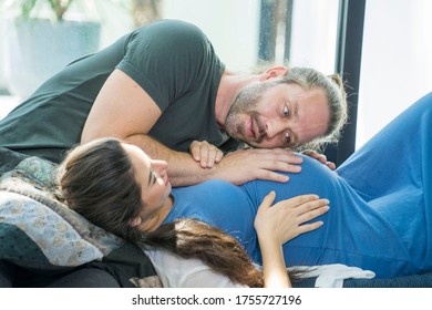 Adolescent Pregnancy Concept.The Husband Sat On The Sofa, Listened To His Pregnant Wife, And Was Happily Talking With The New Family In The House