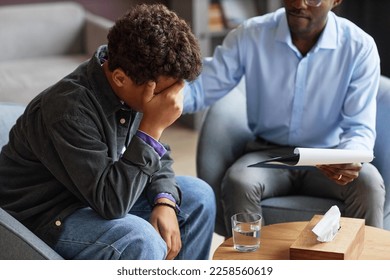 Adolescent psychologist reassuring crying teenage boy
