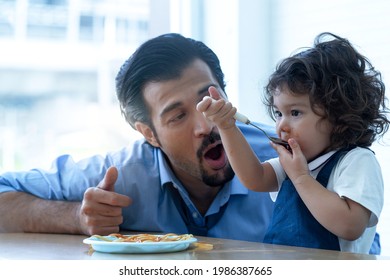 Adorable 2 Years Old Girl Eating Spaghetti Pasta Enjoyment With Their Hands, And Father Sitting Nearby 