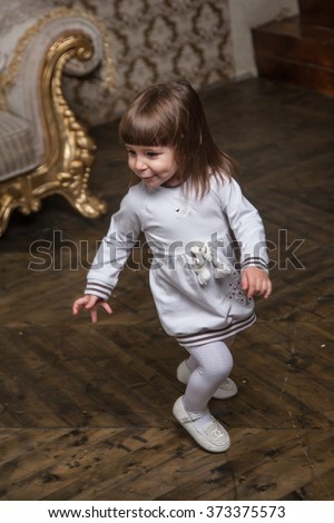 An adorable 2-year-old girl has fun and runs around the room