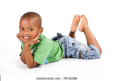 Adorable 3 Year Old Black Or African American Boy With A Big Smile Lying On The Floor With His Feet Up Looking At You