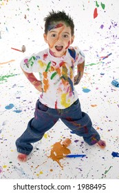 Adorable 3 Year Old Boy Child Covered In Bright Paint.  Mess Of Paint On Wall, Floor, And Child.