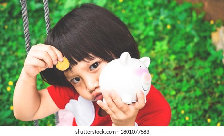 Adorable 3 Years Old Child Holding Coins And Piggy Bank In Hand, Saving Money For Dream, Future And Education For Children Concept.