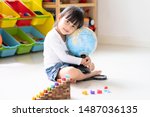 Adorable 4 years old asian little girl is hugging the bilingual globe model contain english and thai language, concept of save the world and learn through play activity for kid education at home.