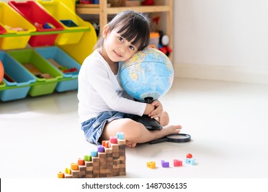 Adorable 4 Years Old Asian Little Girl Is Hugging The Bilingual Globe Model Contain English And Thai Language, Concept Of Save The World And Learn Through Play Activity For Kid Education At Home.