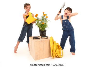 Adorable 6 And 7 Year Old French American Kids Being Goofy With Potted Marigold Plant Over White Background.