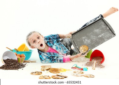 Adorable 7 year old girl baking cookies falling making mess over white background.
