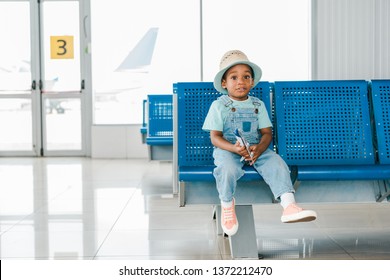 Adorable African American Boy Sitting With Toy Plane In Airport