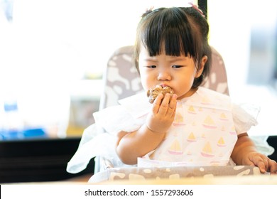 Adorable Asian Baby Girl Is Eating By Herself. She Is Trying New Menu From Mom. Hungry And Unhappy Face. Baby Led Weaning. Baby And Food Concept