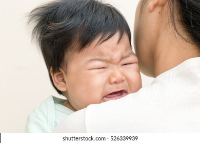 Adorable Asian Baby Sick And Crying On Mom Shoulder.