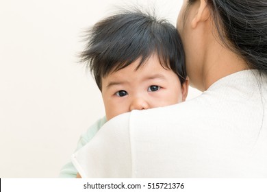 Adorable Asian Baby Sick And Unhappy On Mom Shoulder.