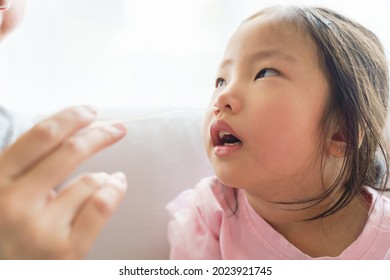 Adorable Asian Girl Kid Getting Swab Test At Home By Her Parent. Rapid Self Test For Covid-19, Antigen Test Kit, Quick Check Before School. New Normal Routine For Kid. Selective Focused.