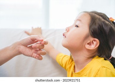 Adorable Asian Girl Kid Getting Swab Test At Home By Her Parent. Rapid Self Test For Covid-19, Antigen Test Kit, Quick Check Before School. New Normal Routine For Kid.