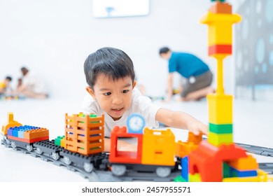 Adorable asian kindergarten boy enjoying play toy train block on white room education learnning concept - Powered by Shutterstock