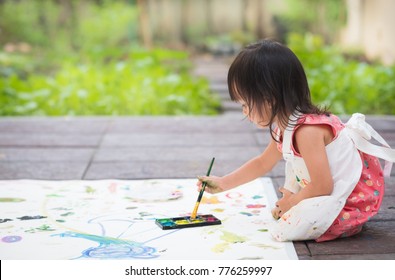 Adorable Asian Little Girl Is Playing By Color Painting In The Garden Outside The House And Her Body Covered With The Colors, Concept Of Art Education Activity For Preschool Kid.