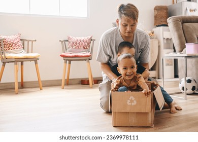 Adorable Asian little kid inside carboard box showing happy expression while playing with father at home. - Shutterstock ID 2369978111