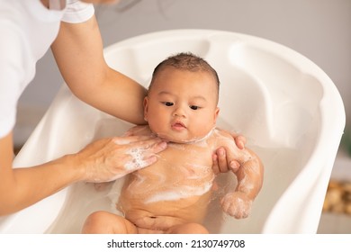 Adorable of asian newborn baby bathing in bathtub.mother bathing her son in warm water.Happy adorable newborn infant smile in tub relax and comfortable.Newborn baby care concept - Shutterstock ID 2130749708