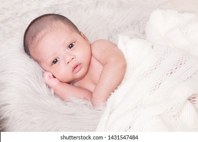 Adorable Asian Newborn Baby In Wrap Sleeping On White Blanket Background. Portrait Of Newborn Boy Sleep On Bed. Open Eyes. 1 Months Old Baby. 