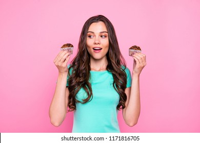 Adorable attractive nice charming amazed curly-haired brunette young smiling girl holding showing two cupcakes. Isolated over pink pastel background - Powered by Shutterstock