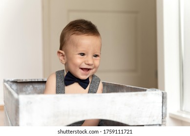 Adorable Baby Boy With Bowtie Sitting In Basket.