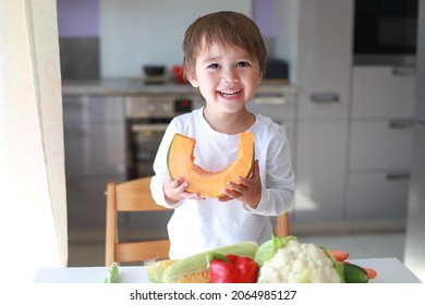 Adorable Baby Boy Holding A Slice Of Fresh Pumpkin With Smiling Face. Happy Mixed Race Asian-German Child With Healthy Vegetables Prepared For Cooking At Kitchen Home Background. Kid With Organic Food