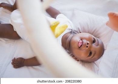 Adorable baby boy lying in his crib playing with mobile at home in the bedroom