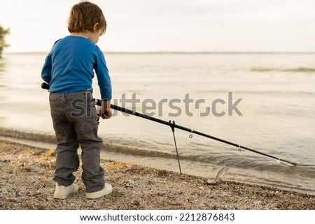 Adorable baby boy on river with fishing-rod and fishing. little child fishing on lake. baby in nature