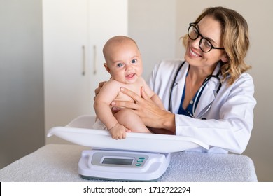Adorable baby boy sitting on scale during weight measuring exam at doctor office. Pediatrician weighting baby girl on scales. Child specialist making an assessment of a baby’s growth progress.