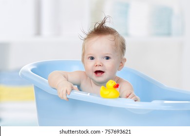 adorable baby boy taking bath in blue tub
