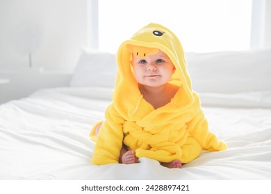 An Adorable baby boy in white sunny bedroom wearing duck Bathrobe