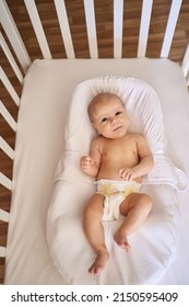 Adorable Baby In Co-sleeper Crib Attached To Parents' Bed. Little Child Having A Day Nap In Cot. Sleep Training Concept. Infant Kid In Sunny Nursery