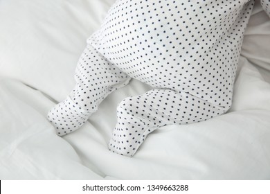 Adorable Baby In Cute Footie On White Sheet, Closeup