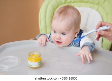 Adorable Baby Eating In High Chair. Baby's First Solid Food