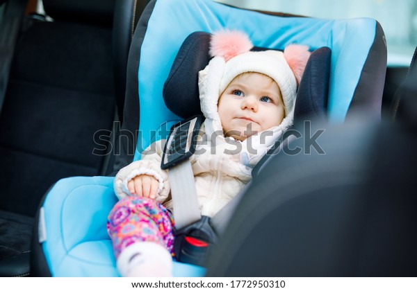 Adorable baby\
girl with blue eyes sitting in car seat. Toddler child in winter\
clothes going on family vacations and jorney. Safe travel, children\
safety, transportation\
concept.