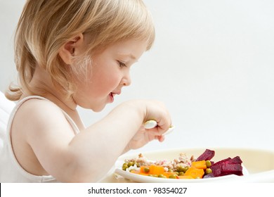 Adorable baby girl eating fresh vegetables; healthy eating for a baby
