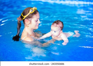 Adorable baby girl enjoying swimming in a pool with her mother, early development class for infants teaching children to swim and dive