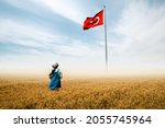 Adorable baby girl is in a field with fog and looking to Turkish national flag admiringly.