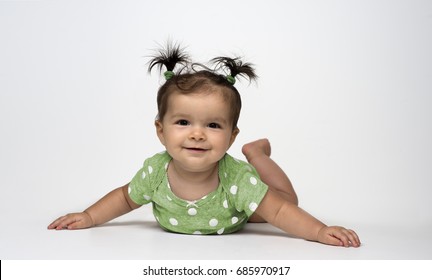 Adorable Baby Girl In Green Polka Dot Onesie Lying On Stomach