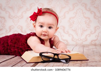 Adorable kleine Mädchen auf dem Boden liegen und ein Buch mit Brille und Band lesen