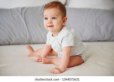 Adorable Baby Girl Sitting On Bed 