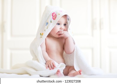 Adorable baby girl sitting under a hooded towel after bath - Powered by Shutterstock