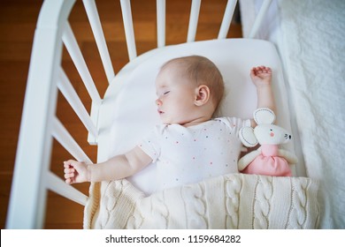 Adorable baby girl sleeping in co-sleeper crib attached to parents' bed. Little child having a day nap in cot. Infant kid in sunny nursery - Powered by Shutterstock