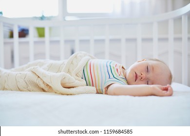 Adorable Baby Girl Sleeping In Co-sleeper Crib Attached To Parents' Bed. Little Child Having A Day Nap In Cot. Infant Kid In Sunny Nursery