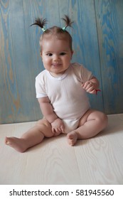 Adorable Baby Girl with two tails Sitting on a wooden floor