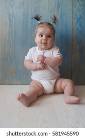 Adorable Baby Girl with two tails Sitting on a wooden floor