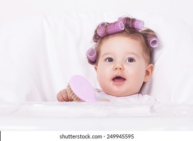 Adorable baby with hair curlers and comb