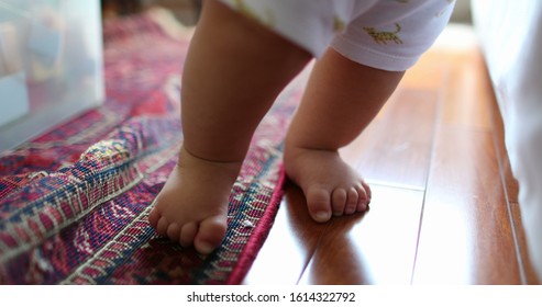 
Adorable Baby Infant Child Learning To Stand Up. Cute Toddler Standing Leaning On Couch